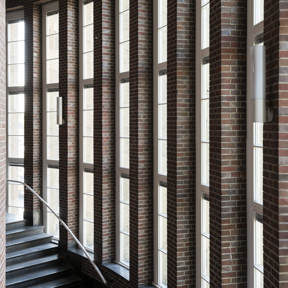 Architekturfotografie der Treppe im NRW Forum vor Fenstern Richtung Rhein und Pfeilern aus Backstein