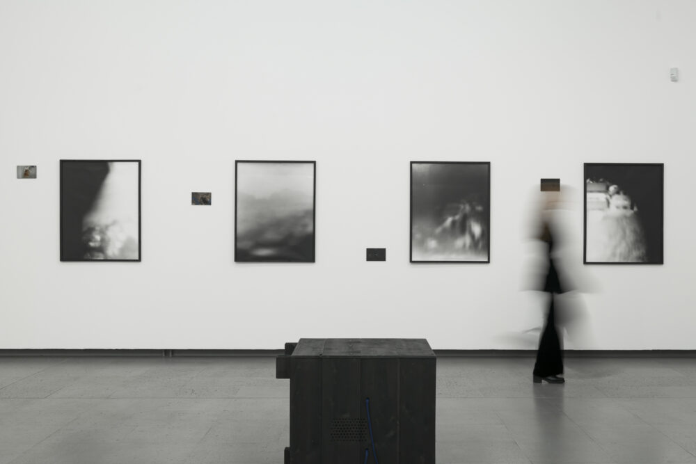 Eine Person läuft durch die Ausstellung gute Aussichten mit Fotografien von Marco Mehringer im Hintergrund