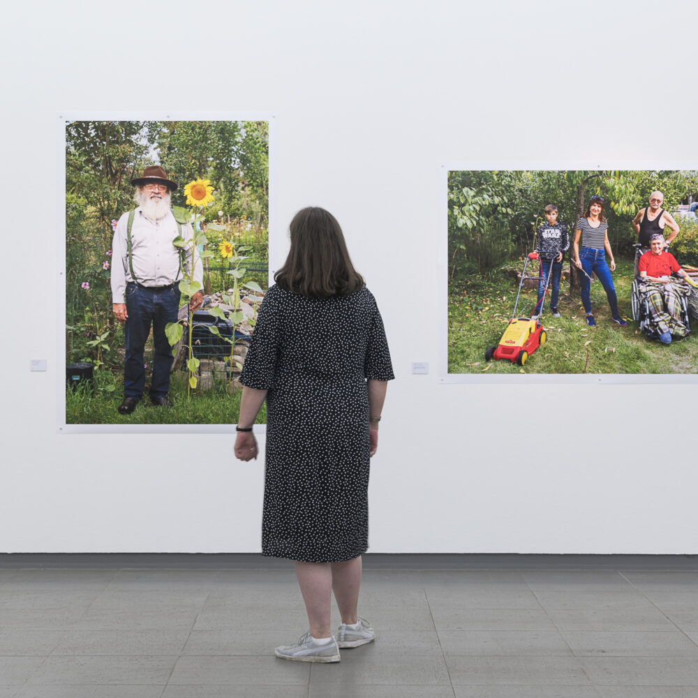 Eine Frau sieht sich Bilder von Kleingärtnern von Martin Parr an