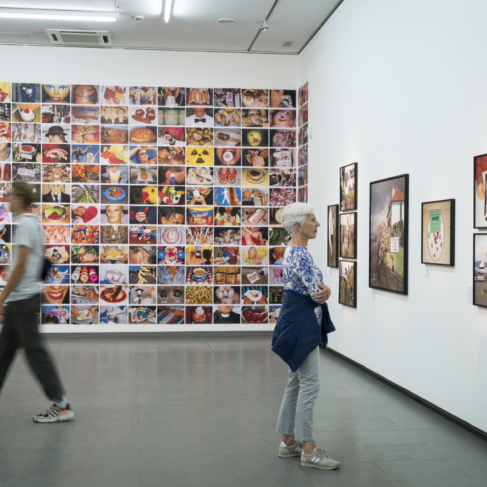 Zwei Personen betrachen Kunstwerke in der Martin Parr Retrospektive