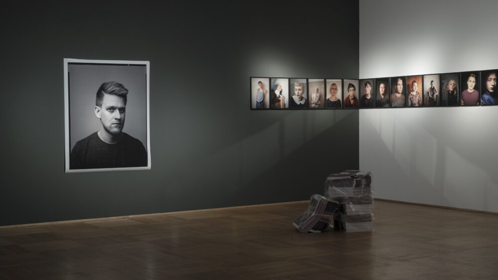 Several portrait photos hang on a black and a white wall in the NRW Forum