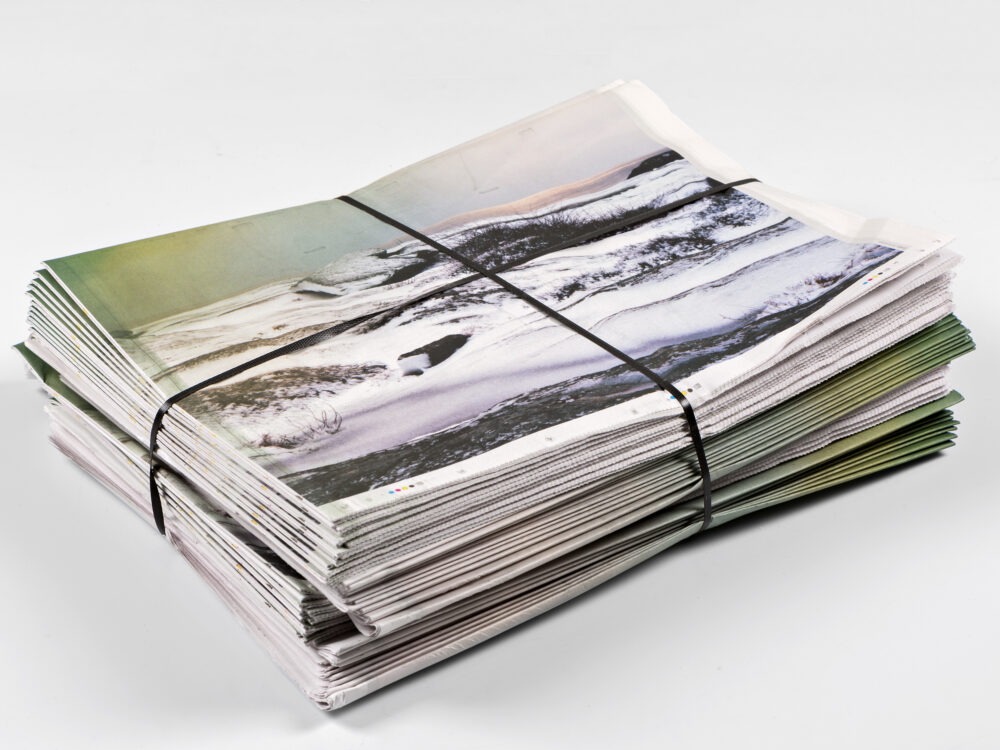 A bundled stack of newspapers lies on a white background