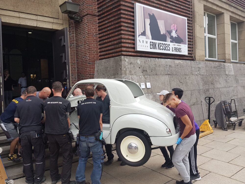 Several craftsmen carrying a oldtimer car into the NRW Forum