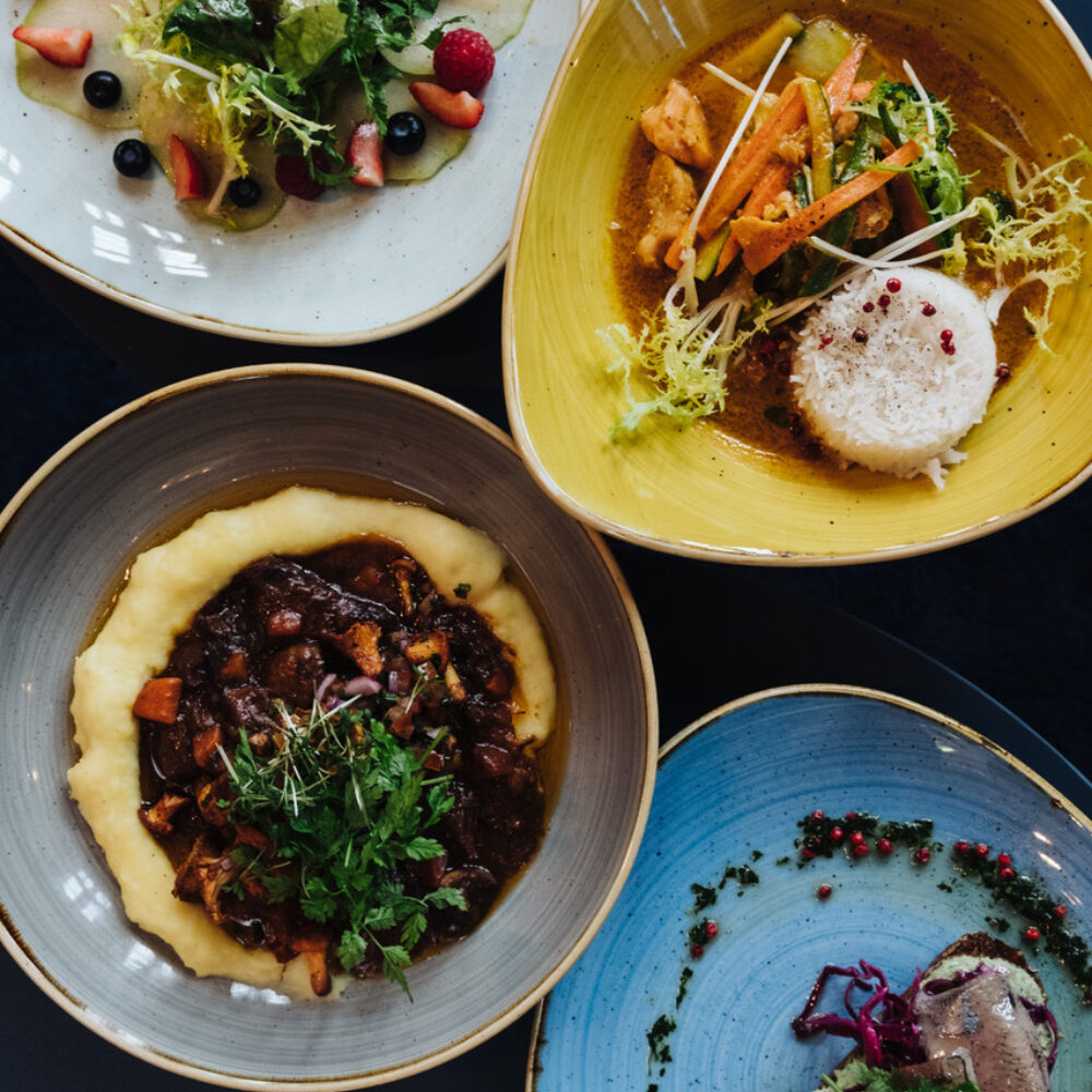 Four colourful plates with different, decoratively arranged dishes